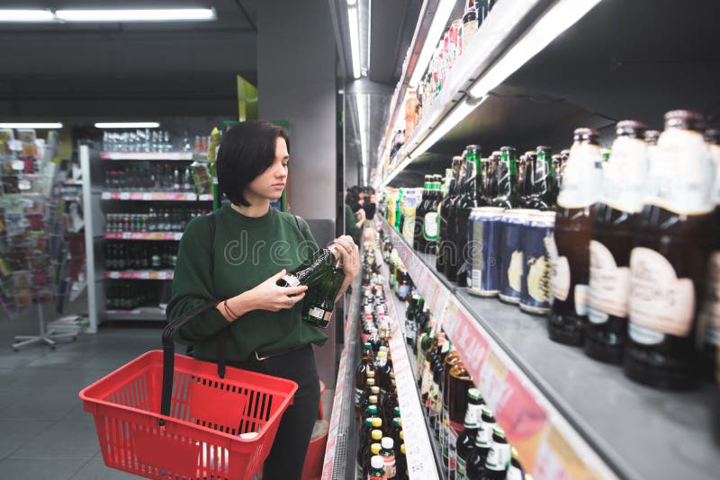 Ein Mädchen mit einem roten Korb wählt Alkohol in einem Supermarkt Für Bier im Geschäft kaufen stockbild Ein Mädchen mit einem roten Korb wählt Alkohol in einem Supermarkt Für Bier im Geschäft kaufen stockbild