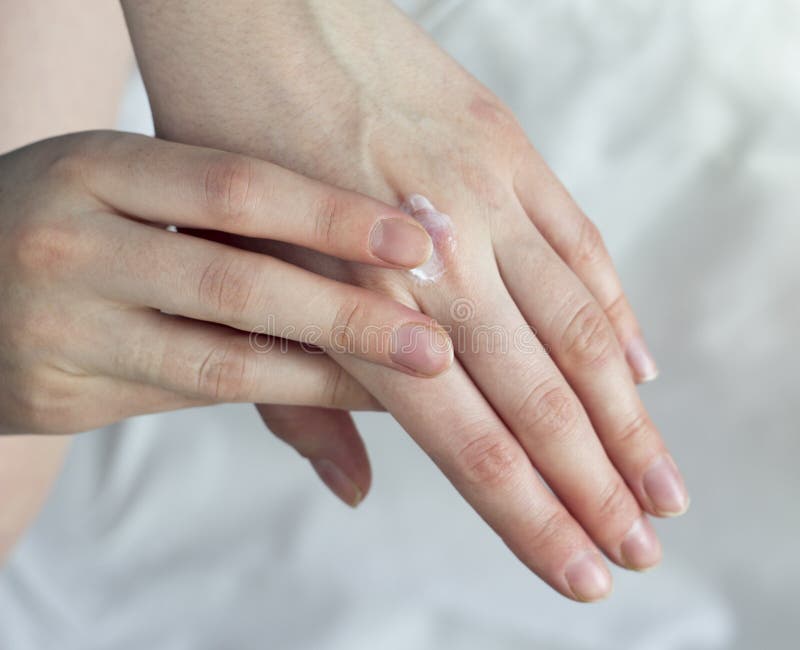 Ein Mädchen schmiert eine Handcreme auf einer weißen Hintergrundcreme lizenzfreie stockbilder Ein Mädchen schmiert eine Handcreme auf einer weißen Hintergrundcreme lizenzfreie stockbilder