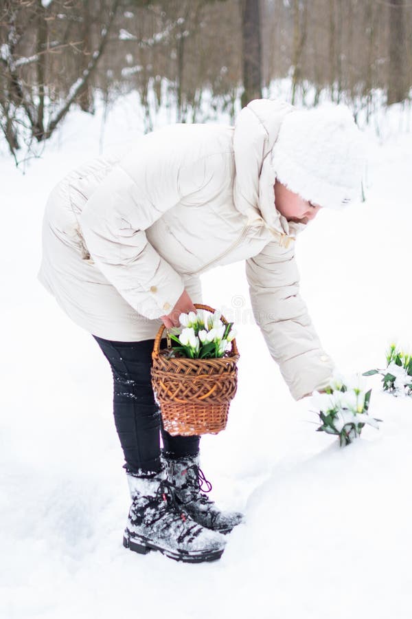 Ein Mädchen in schönen weißen Winterkleidung mit Schneefällen in einem schneebedeckten Winterwald. stockfotografie