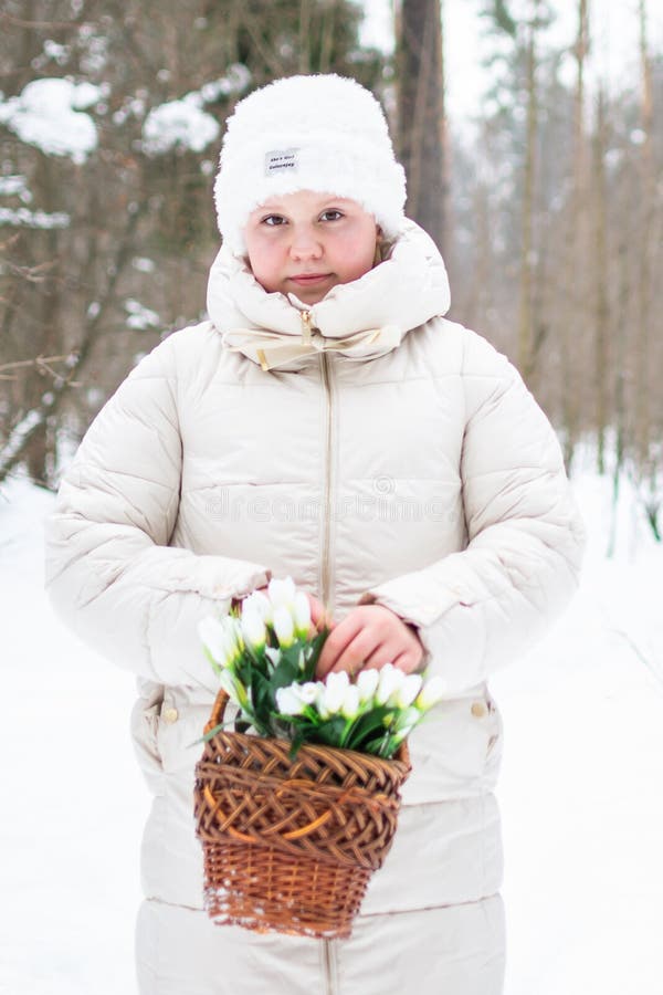 Ein Mädchen in schönen weißen Winterkleidung mit Schneefällen in einem schneebedeckten Winterwald. lizenzfreie stockfotos