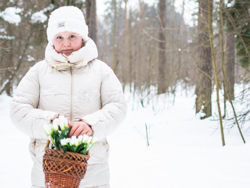 Ein Mädchen in schönen weißen Winterkleidung mit Schneefällen in einem schneebedeckten Winterwald. lizenzfreies stockfoto