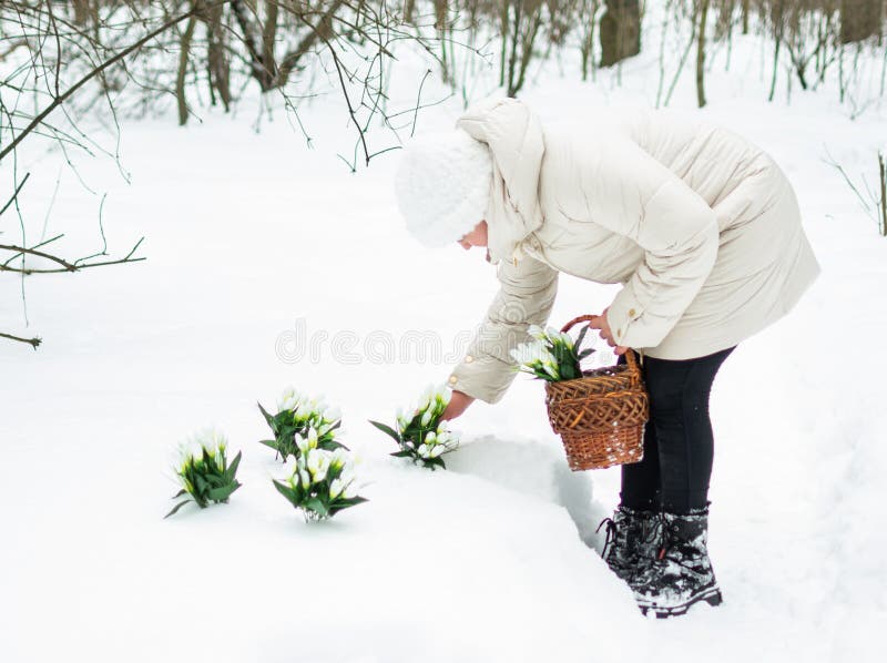 Ein Mädchen in schönen weißen Winterkleidung mit Schneefällen in einem schneebedeckten Winterwald. lizenzfreie stockbilder