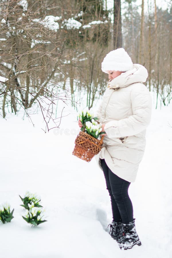 Ein Mädchen in schönen weißen Winterkleidung mit Schneefällen in einem schneebedeckten Winterwald. stockfoto