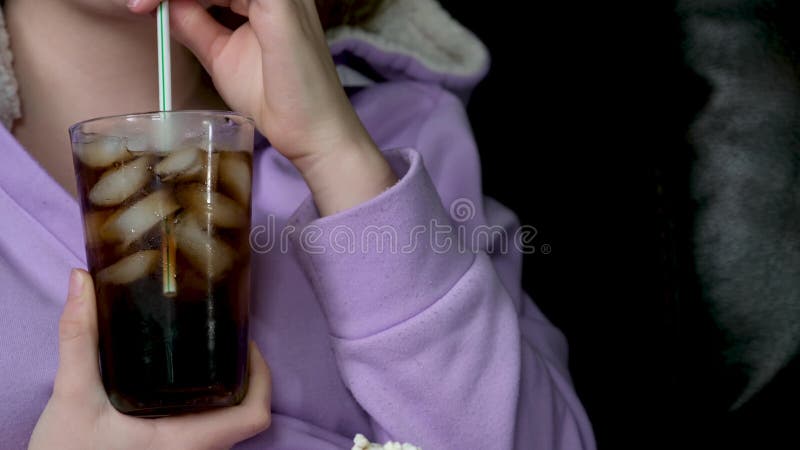 Ein Mädchen sitzt auf einem Sofa und gießt eine Cola in ein Glas