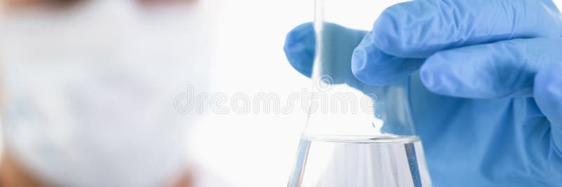 A male chemist holds test tube of glass in his hand overflows a liquid solution of potassium permanganate conducts an analysis of water samples versions of reagents using chemical manufacturing. A male chemist holds test tube of glass in his hand overflows a liquid solution of potassium permanganate conducts an analysis of water samples versions of reagents using chemical manufacturing.