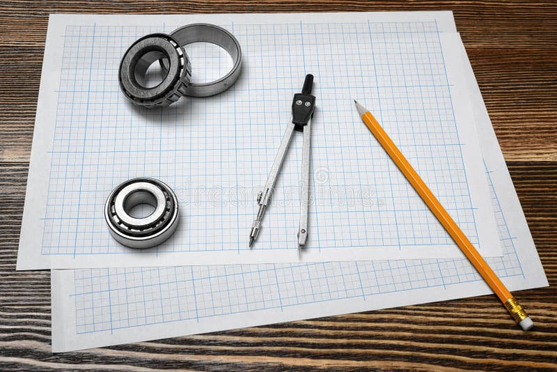 Ein Noniustasterzirkel, der ein Lager, einen Bleistift und einen Zirkel liegend über Zeichenpapier auf hölzernem Hintergrund hält stockfotografie Ein Noniustasterzirkel, der ein Lager, einen Bleistift und einen Zirkel liegend über Zeichenpapier auf hölzernem Hintergrund hält stockfotografie