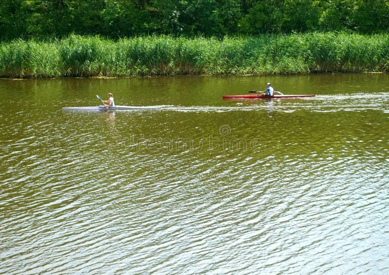 Ein Paar, das auf Kajaks entlang dem Fluss gegen den Strom schwimmt lizenzfreie stockfotos Ein Paar, das auf Kajaks entlang dem Fluss gegen den Strom schwimmt lizenzfreie stockfotos