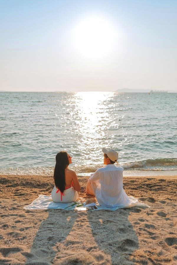 Ein Paar, das einen Strandurlaub in einem tropischen Resort mit einem wunderschön gestalteten Küstenpool bei Sonnenuntergang genie stockbild