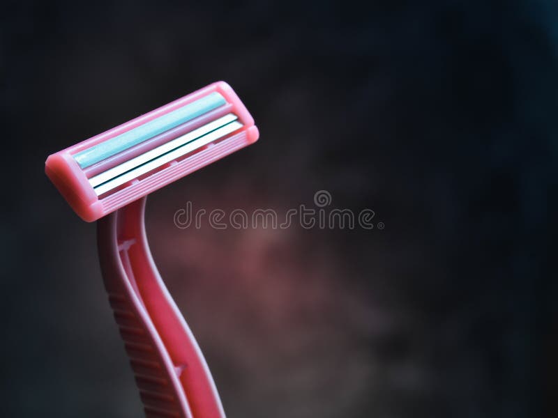 Ein rosa Rasiermesser für Enthaarung gegen eine dunkle Betonmauer stockfoto Ein rosa Rasiermesser für Enthaarung gegen eine dunkle Betonmauer stockfoto