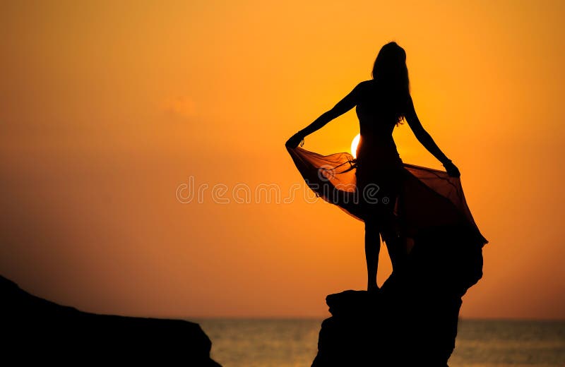 Ein Schattenbild eines jungen Mädchens auf Felsen bei Sonnenuntergang 1 stockbilder Ein Schattenbild eines jungen Mädchens auf Felsen bei Sonnenuntergang 1 stockbilder