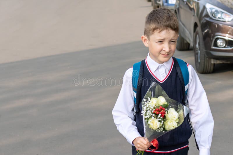 Ein Schuljunge mit einem Blumenstrauß von weißen Rosen in seinem Hand im Freien stockbilder Ein Schuljunge mit einem Blumenstrauß von weißen Rosen in seinem Hand im Freien stockbilder