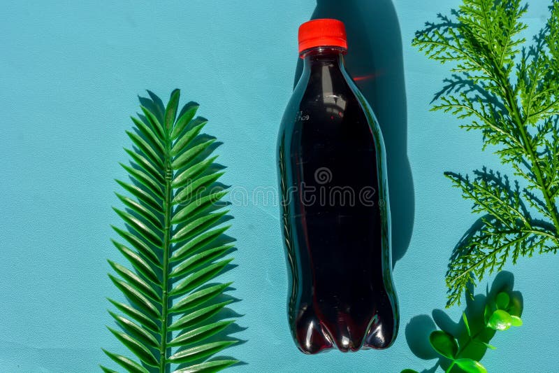 Ein schwarzes Getränk in einer durchsichtigen Flasche mit rotem Deckel stockfoto