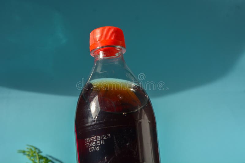 Ein schwarzes Getränk mit einem roten Verschluss in einer durchsichtigen Flasche stockbilder