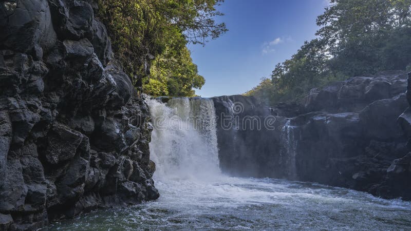 Ein schöner tropischer Wasserfall. Wasserläufe fließen vom Rand des Kamms in den Fluss. lizenzfreie stockfotos