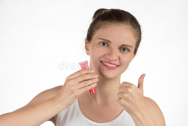 A beautiful young girl applies a persistent liquid shiny red lipstick from a tube to her lips, and then takes it off as a film and shows a thumbs-up. A beautiful young girl applies a persistent liquid shiny red lipstick from a tube to her lips, and then takes it off as a film and shows a thumbs-up