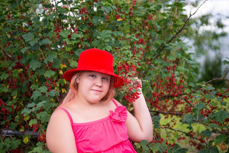 Ein schönes Mädchen in einem hellen Outfit in der Nähe eines roten Johannisbrots. lizenzfreie stockbilder