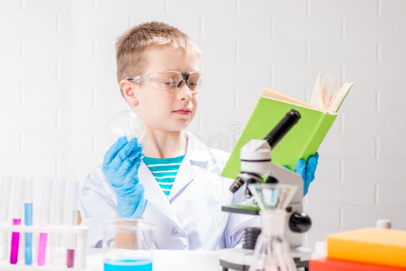 Ein Schüler mit einem Mikroskop und Buch untersucht Chemikalien in Reagenzgläsern führt Experimente ein Porträt auf einem weißen stockfotografie
