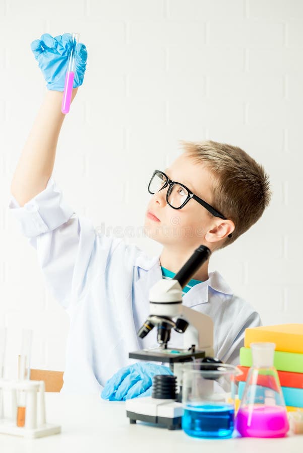 Ein Schüler mit einem Mikroskop untersucht Chemikalien in Reagenzgläsern führt Versuche ein Porträt auf einem weißen Hintergrund. stockbilder