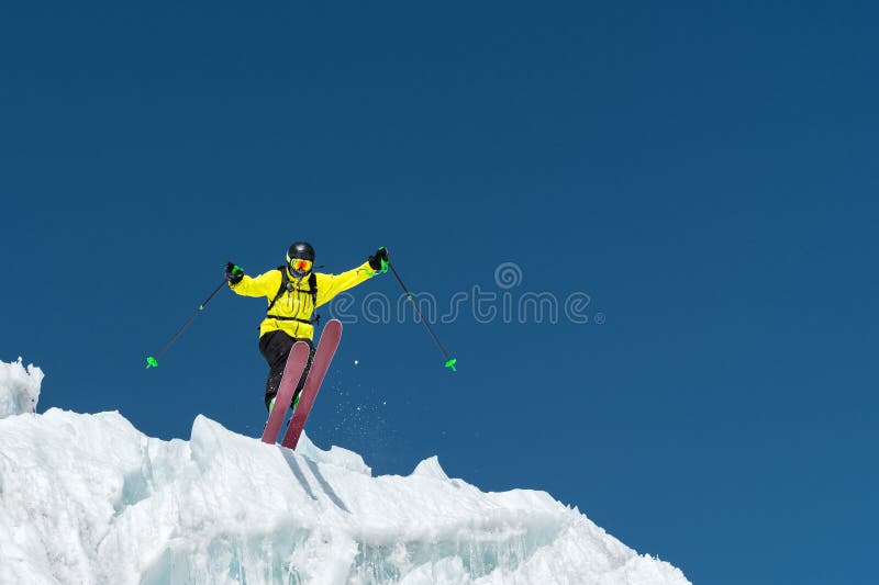 Ein springender Skifahrer, der von einem Gletscher gegen ein Blau himmelhoch in den Bergen springt Berufsskifahren lizenzfreie stockbilder Ein springender Skifahrer, der von einem Gletscher gegen ein Blau himmelhoch in den Bergen springt Berufsskifahren lizenzfreie stockbilder