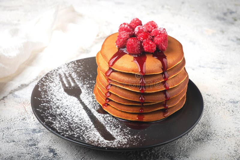 Ein Stapel Pfannkuchen auf einer Platte mit Himbeeren und Beerensoße lizenzfreies stockbild Ein Stapel Pfannkuchen auf einer Platte mit Himbeeren und Beerensoße lizenzfreies stockbild
