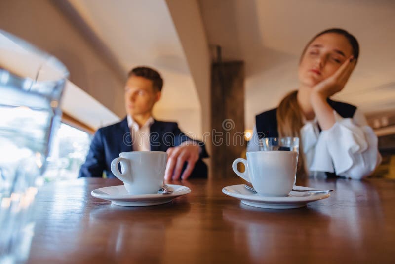 Ein stilvolles Paar trinkt Morgenkaffee am Caf?, das M?dchen schl?ft, der Junge schaut heraus das Fenster lizenzfreie stockfotos Ein stilvolles Paar trinkt Morgenkaffee am Caf?, das M?dchen schl?ft, der Junge schaut heraus das Fenster lizenzfreie stockfotos