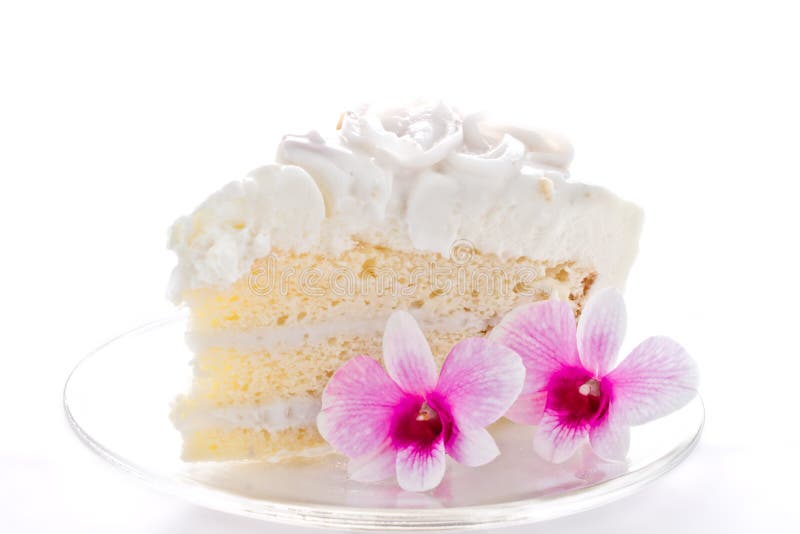 A piece of coconut cake with two orchids on white background. A piece of coconut cake with two orchids on white background