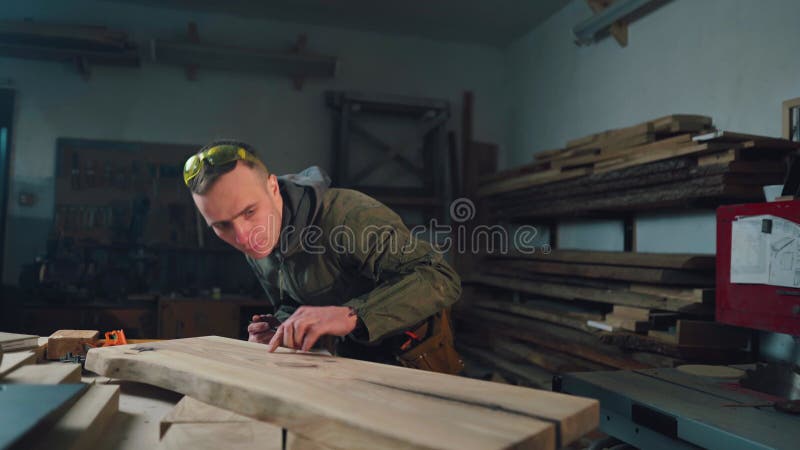Ein Tischler in einer Tischlerei misst ein Brett, um ein Holzprodukt herzustellen. Holzarbeiter