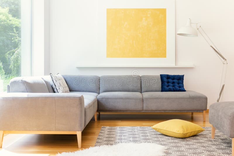 Ein unbedeutendes, gelbes Plakat und ein Weiß, eine industrielle Stehlampe in einem sonnigen Wohnzimmerinnenraum mit einer kopier