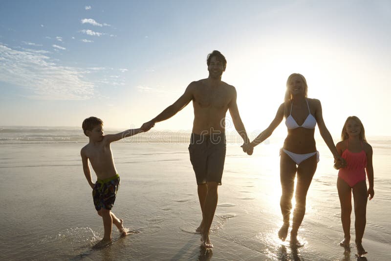 Ein weiterer erstaunlicher Tag, der zum Ende führt. eine glückliche Familie, die bei Sonnenuntergang am Strand spaziert. stockbild