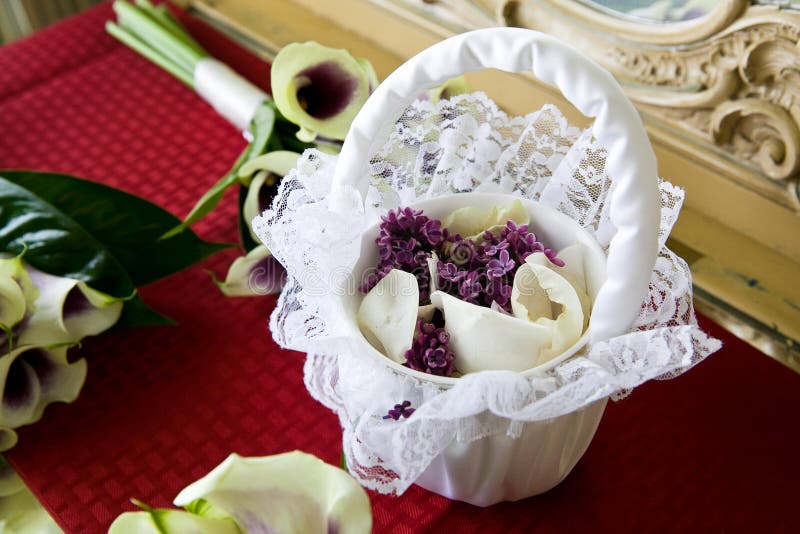 Ein weißer Korb der Blumenmädchen voll von purpurroten Blumen und von weißen rosafarbenen Blumenblättern stockfotos Ein weißer Korb der Blumenmädchen voll von purpurroten Blumen und von weißen rosafarbenen Blumenblättern stockfotos
