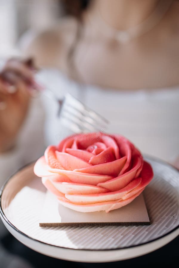 Ein weißes Oberteil hält eine Gabel, um ein zartes rosarotes Dessert zu genießen lizenzfreies stockfoto