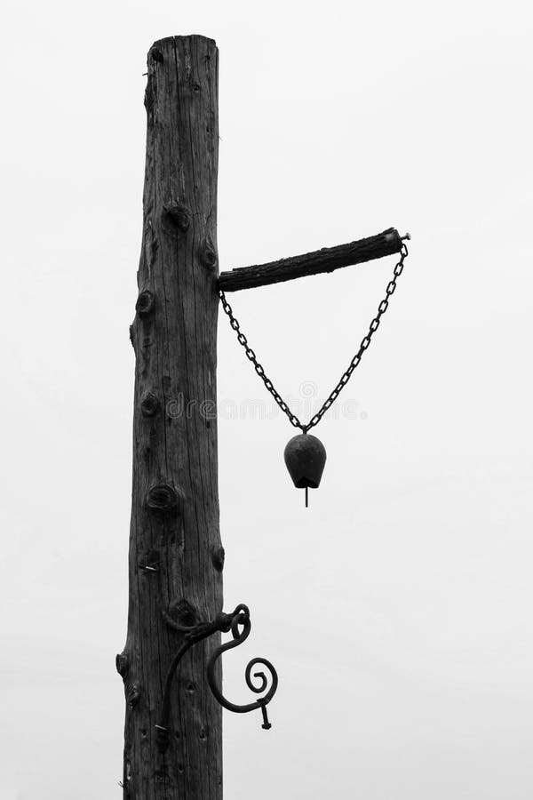Eine alte Glocke, die auf einem Bauernhof auf einer Holzpfeiler montiert wird - Schwarz und Weiß stockfoto Eine alte Glocke, die auf einem Bauernhof auf einer Holzpfeiler montiert wird - Schwarz und Weiß stockfoto