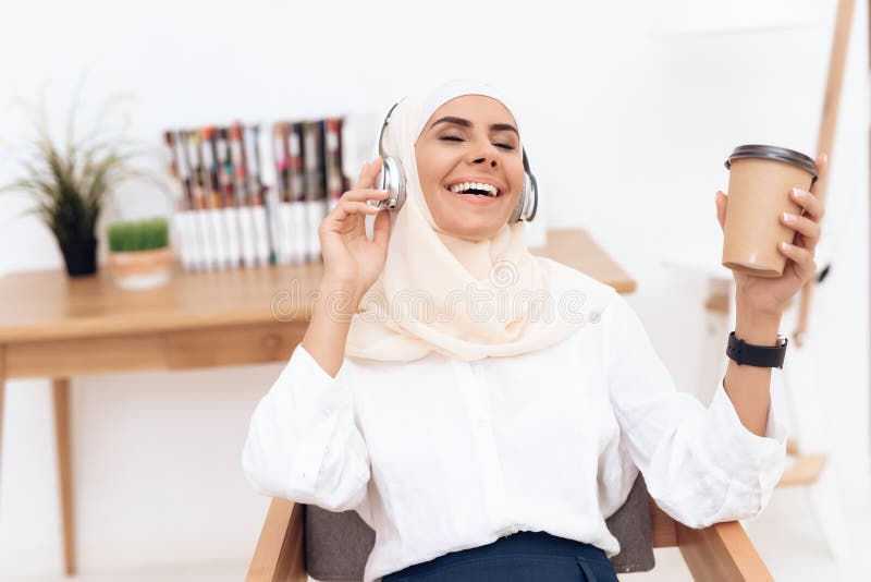 Eine arabische Frau im hijab hört Musik auf Kopfhörern lizenzfreies stockbild Eine arabische Frau im hijab hört Musik auf Kopfhörern lizenzfreies stockbild