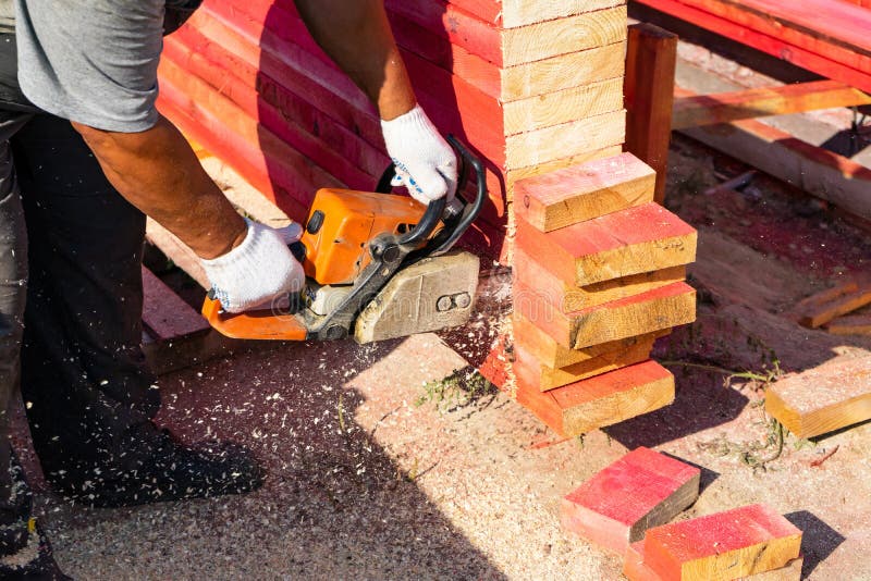 Eine Arbeitskraft sägt weg von einem Kettensägenholz Brett Windows, Haustür und Garage lizenzfreie stockfotos Eine Arbeitskraft sägt weg von einem Kettensägenholz Brett Windows, Haustür und Garage lizenzfreie stockfotos