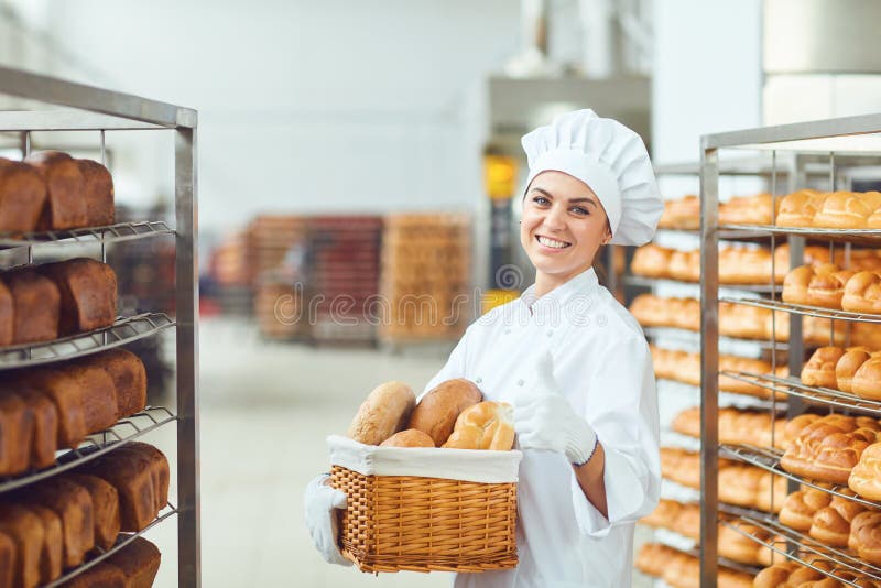 Eine Bäckerfrau, die einen Korb von gebacken in ihren Händen an der Bäckerei hält lizenzfreies stockbild Eine Bäckerfrau, die einen Korb von gebacken in ihren Händen an der Bäckerei hält lizenzfreies stockbild