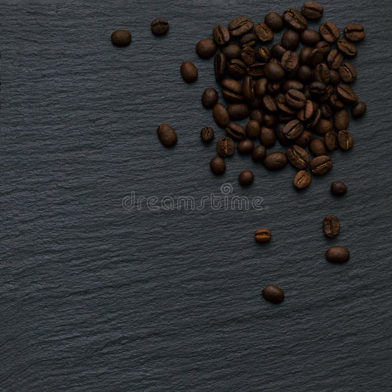 Eine Ecke vieler Kaffeebohnen auf einem schwarzen strukturierten Hintergrund des Schiefersteins. Kopienraum für Text