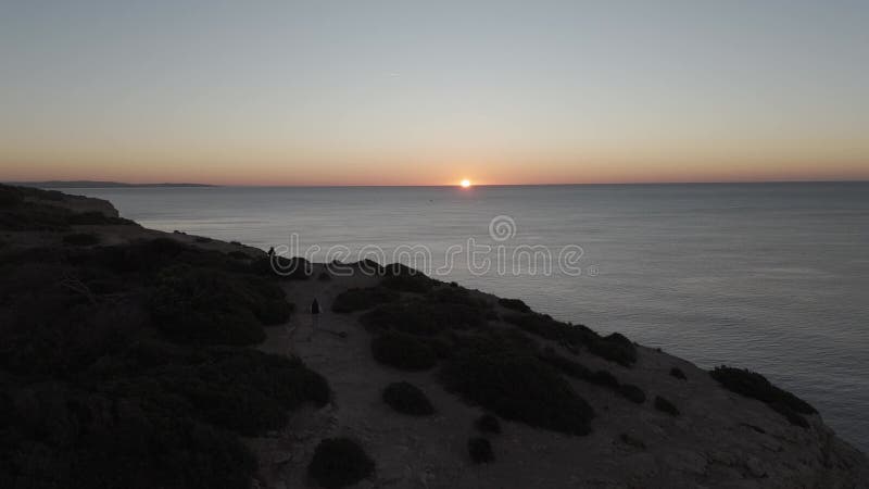 Eine Einzelfrau, die ihr Stativ auf zerklüfteten Algarve-Felsen in der Nähe von carvoeiro portugal aufbaut, um das stock video footage