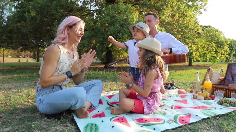 Eine Familie hat Spaß, während eine Picknmutter mit ihrer Tochter spielt und Vater spielt Gitarre