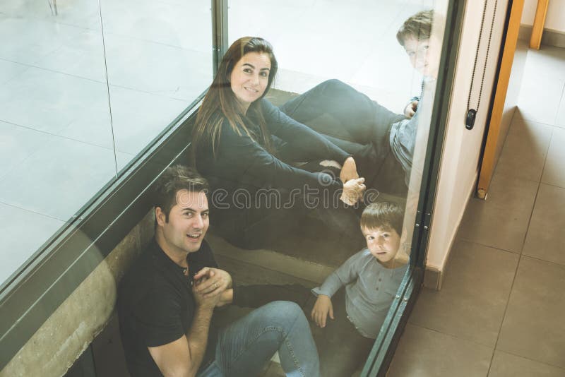 Eine Familie mit den Kindern, die zu Hause auf der Treppe glücklich und dem Lächeln sitzen Entzückende Paare mit Kindern zu Hause lizenzfreies stockbild Eine Familie mit den Kindern, die zu Hause auf der Treppe glücklich und dem Lächeln sitzen Entzückende Paare mit Kindern zu Hause lizenzfreies stockbild