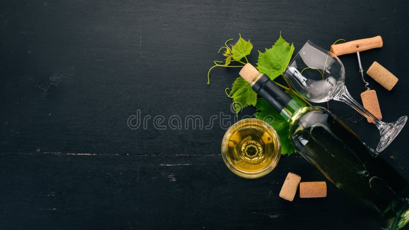 Eine Flasche Weißwein mit Gläsern und Weintrauben Traubenblätter Oberansicht Auf schwarzem Holzboden stockbilder