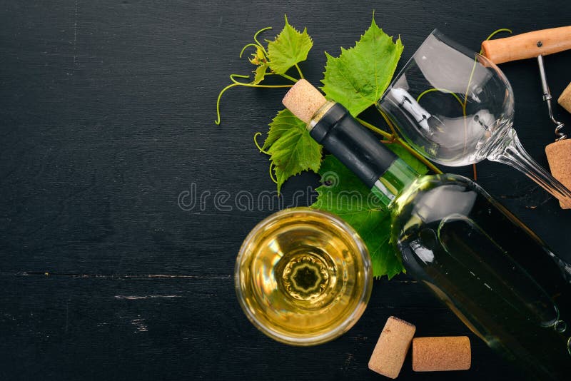 Eine Flasche Weißwein mit Gläsern und Weintrauben Traubenblätter Oberansicht Auf schwarzem Holzboden stockfotos