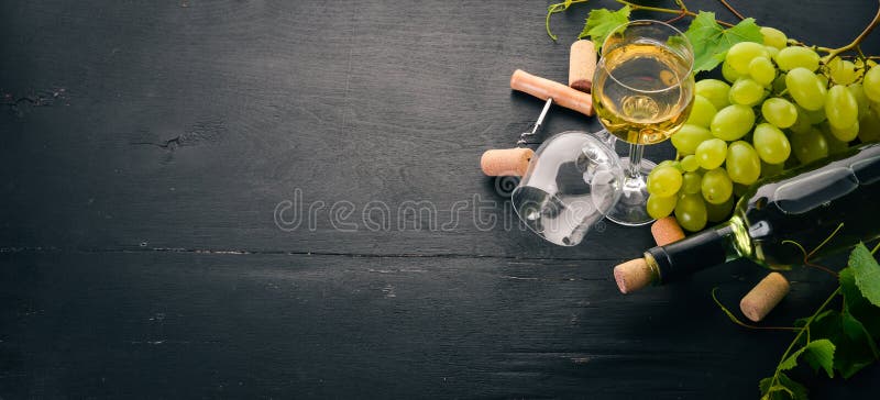 Eine Flasche Weißwein mit Gläsern und Weintrauben Traubenblätter Oberansicht Auf schwarzem Holzboden lizenzfreie stockfotografie
