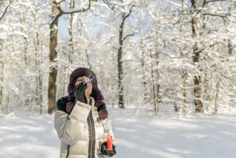 Eine Frau hält eine Handvoll Schnee in ihren Händen und brennt auf ihr durch Wi stockfoto