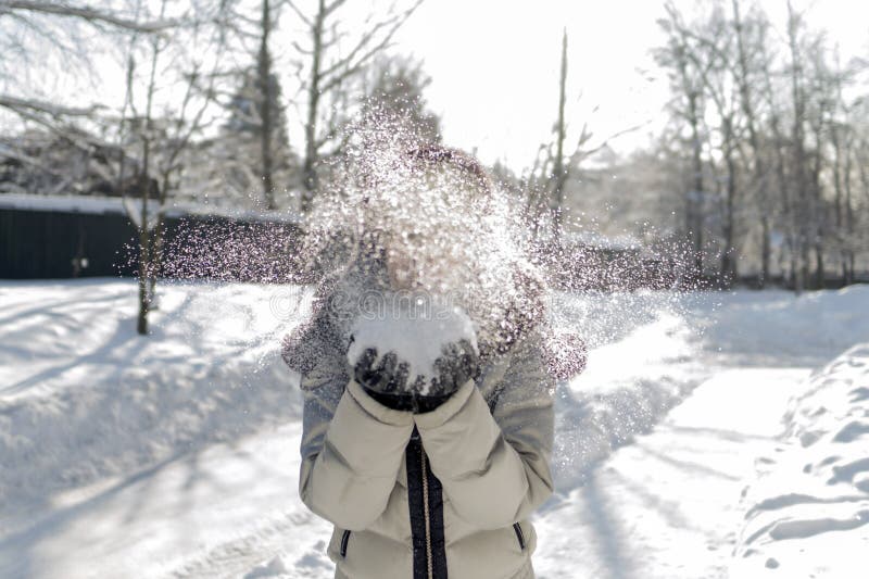 Eine Frau hält eine Handvoll Schnee in ihren Händen und brennt auf ihr durch Wi stockfoto
