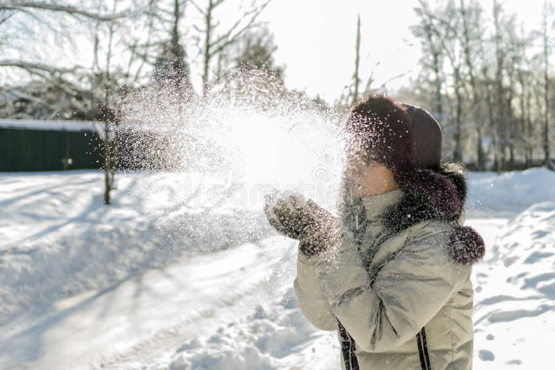 Eine Frau hält eine Handvoll Schnee in ihren Händen und brennt auf ihr durch Wi stockfotografie