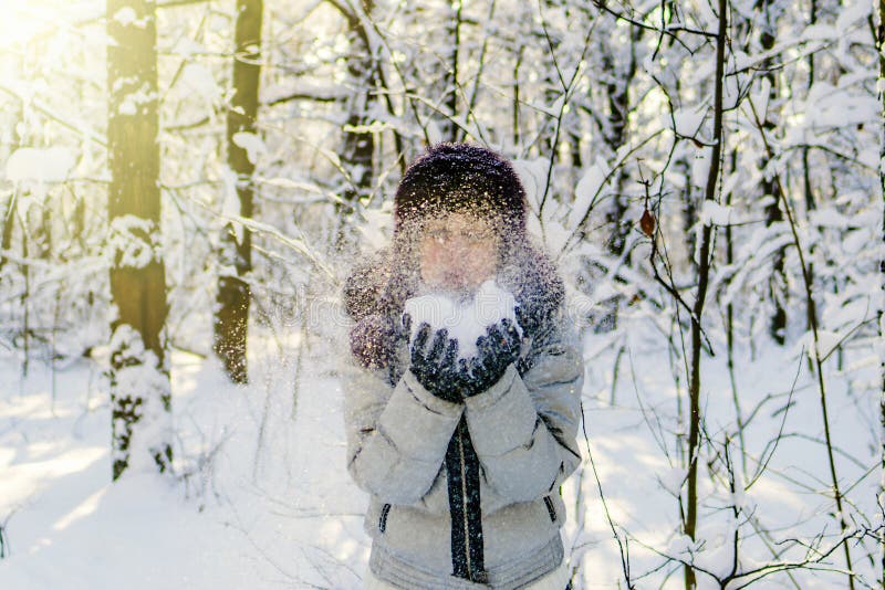 Eine Frau hält eine Handvoll Schnee in ihren Händen und brennt auf ihr durch Wi lizenzfreies stockfoto