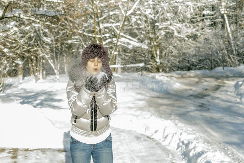 Eine Frau hält eine Handvoll Schnee in ihren Händen und brennt auf ihr durch Wi stockbilder