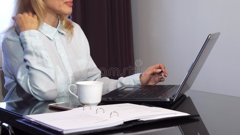 Eine Frau liest wichtige Dokumente in einem Ordner und in den Arten es in einen Laptop stockfoto Eine Frau liest wichtige Dokumente in einem Ordner und in den Arten es in einen Laptop stockfoto