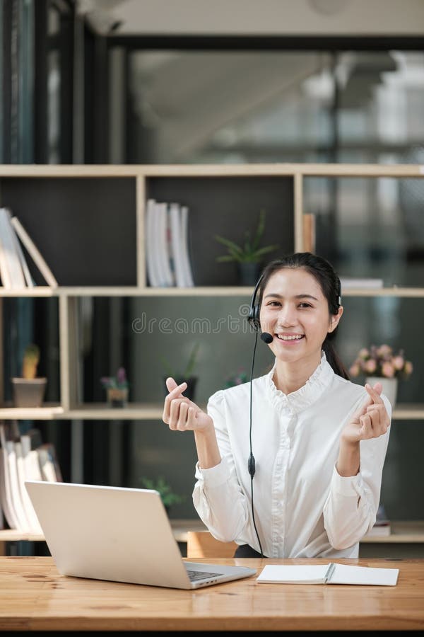 Eine Frau mit einem Headset sitzt an einem Schreibtisch mit Laptop lizenzfreies stockbild