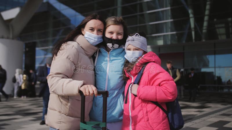 Eine Frau mit zwei Töchtern außerhalb des Gebäudes vor dem Flughafen-Terminal mit Koffern und medizinischem Tragen